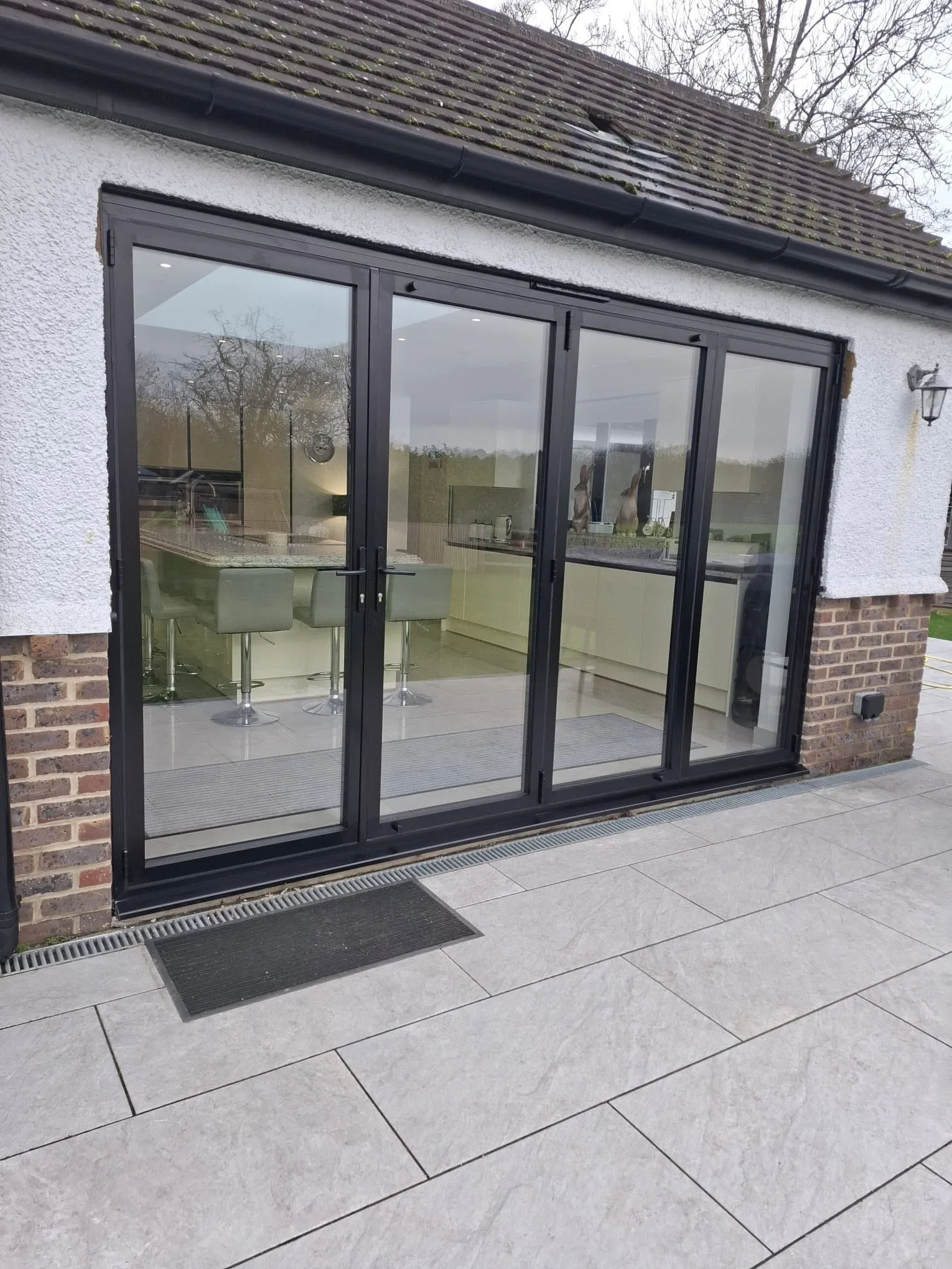 Anthracite aluminium bifold doors closed onto a paved patio