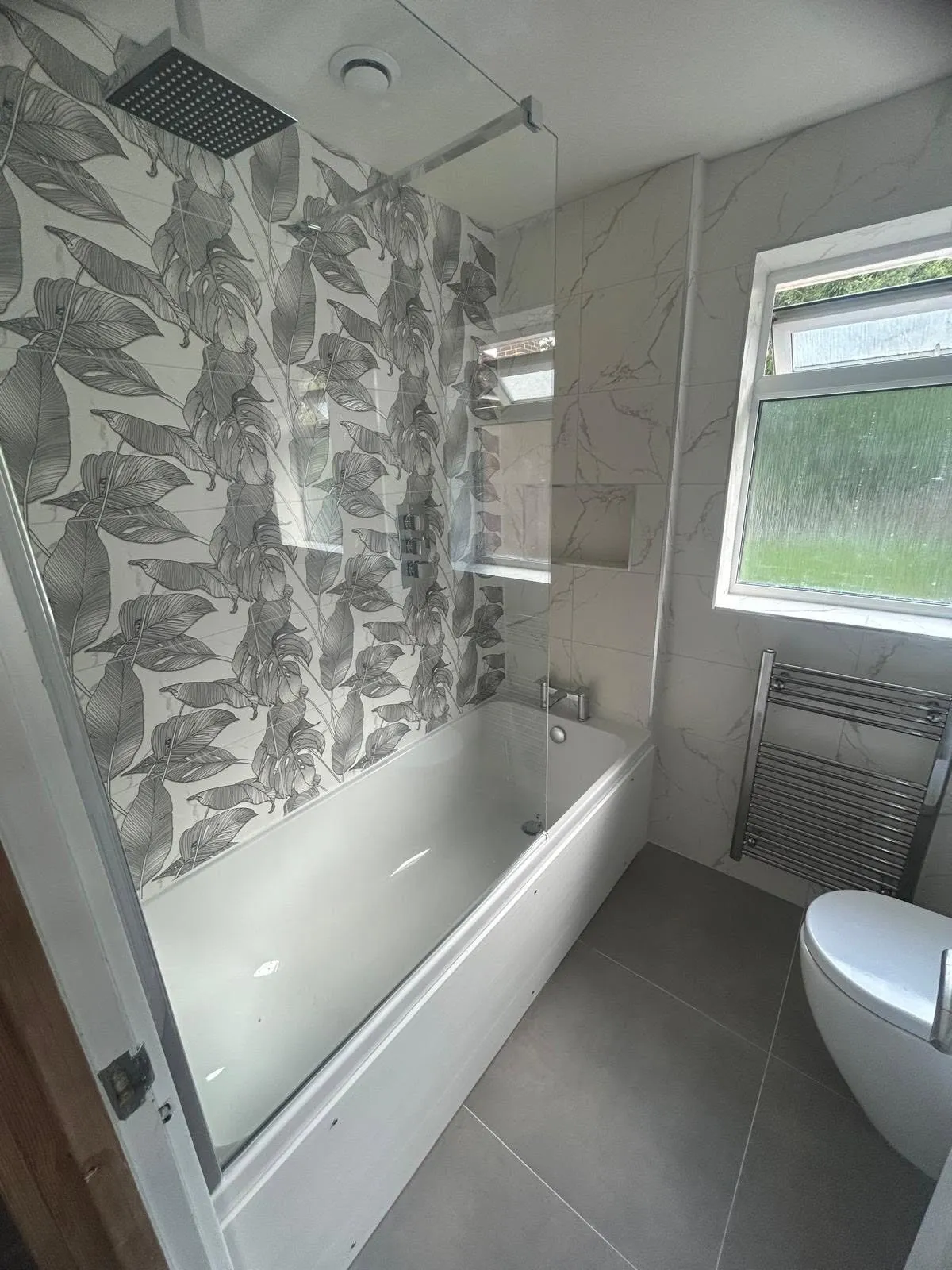 Bathroom with patterned wallpaper and a bath under the window