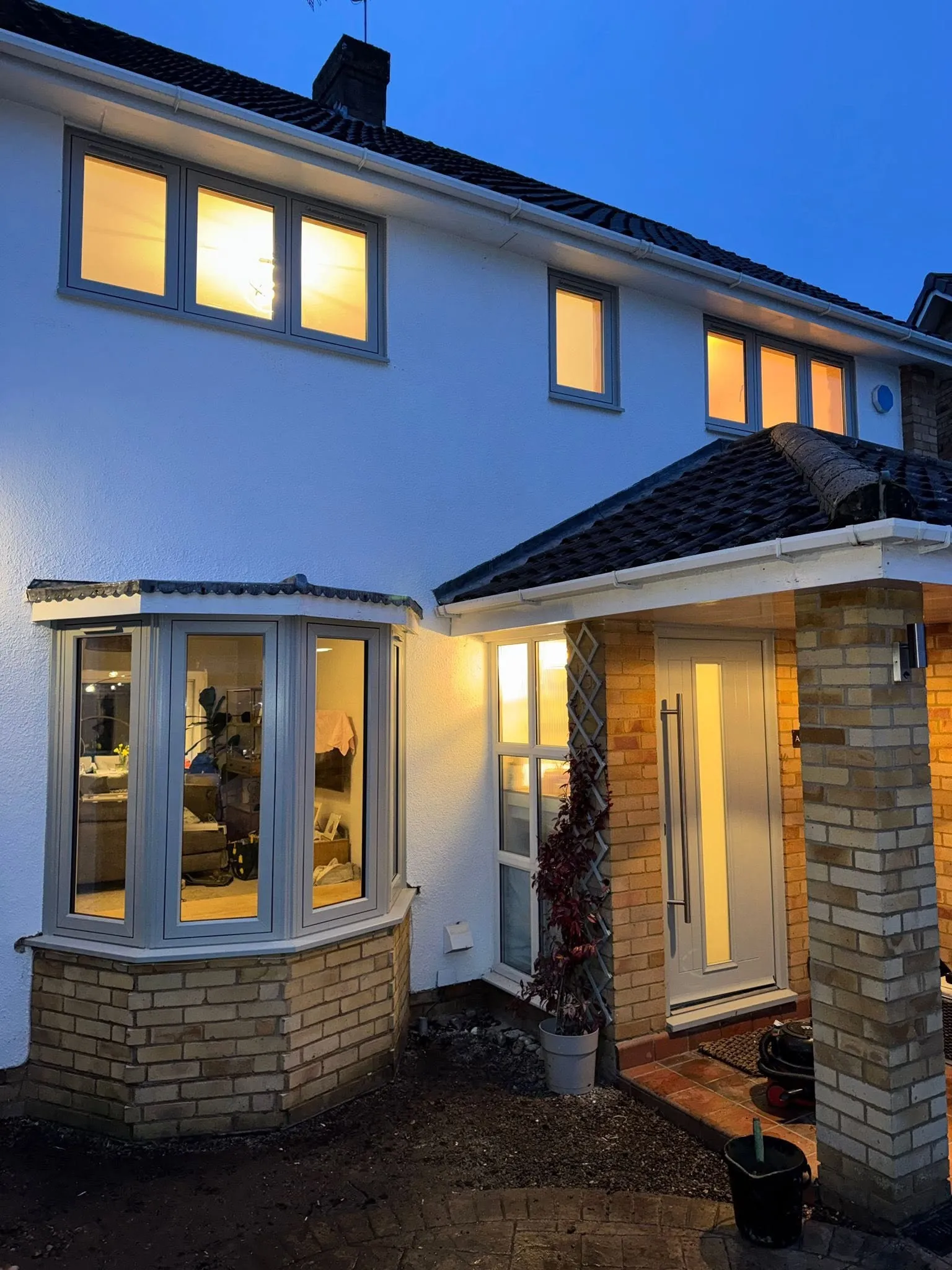 Bay window and composite front door lit from inside at dusk