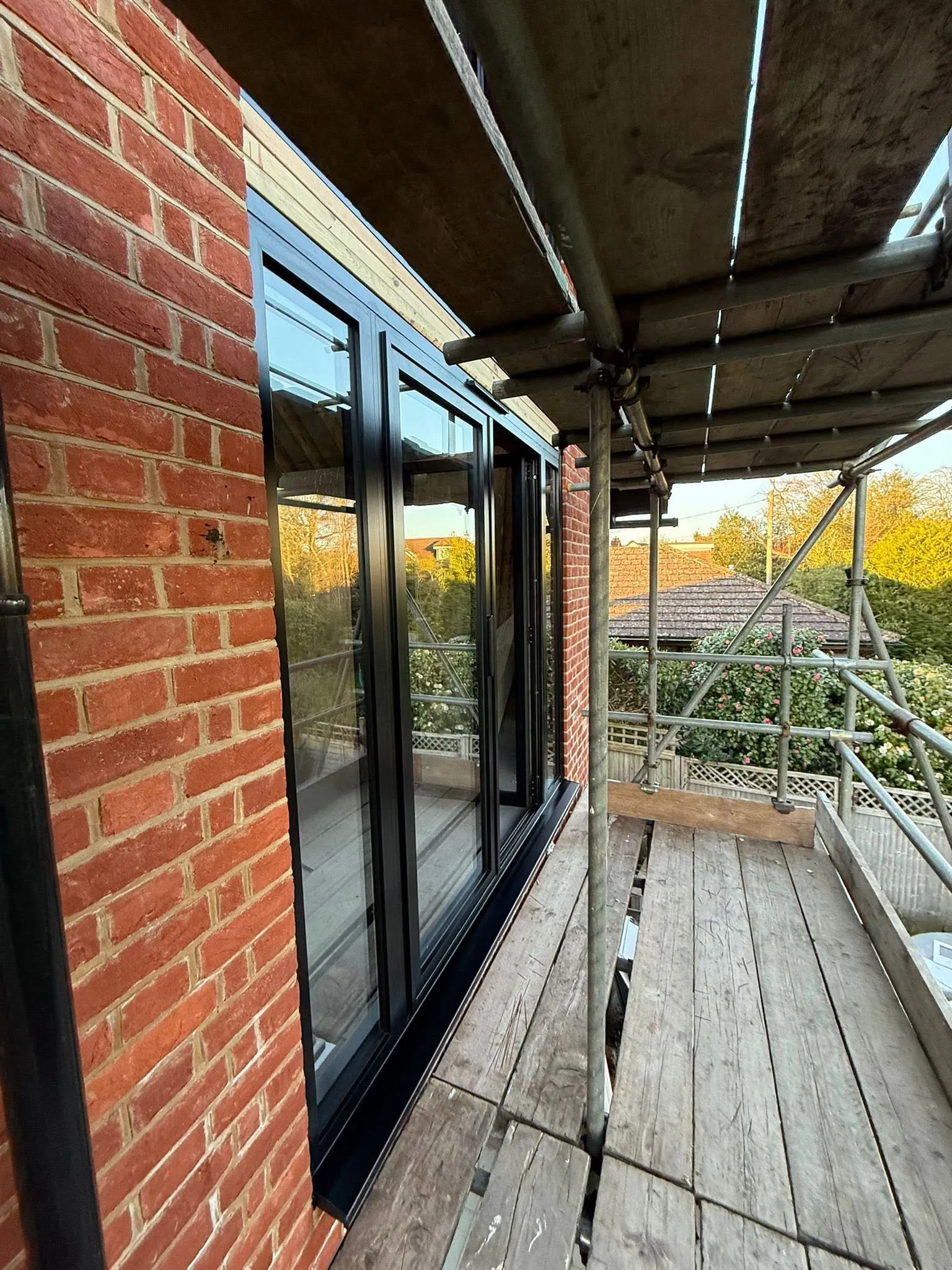 Black aluminium doors on the first floor, seen side-on from the scaffolding