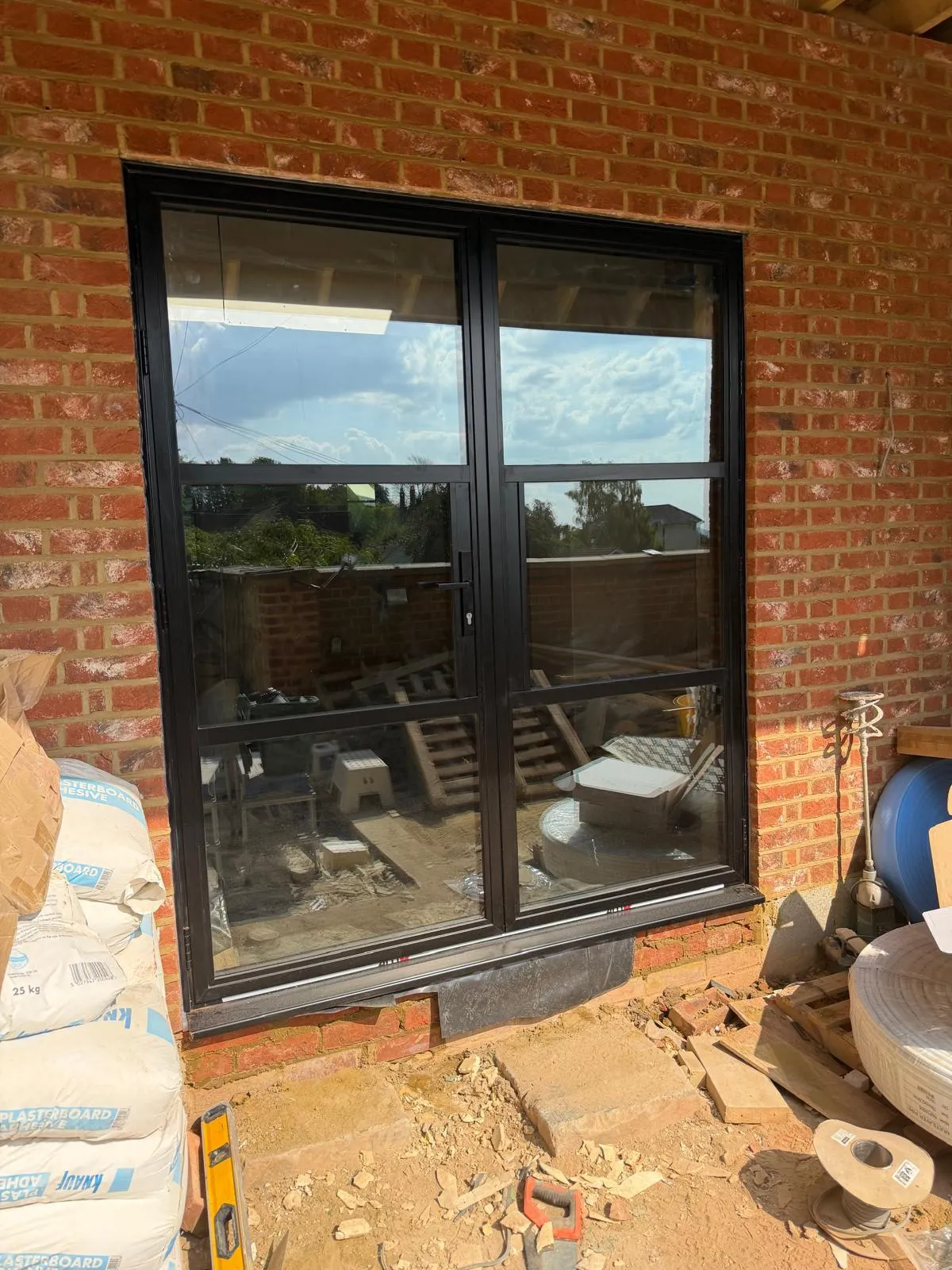 Black aluminium sliding patio doors set into a brick opening