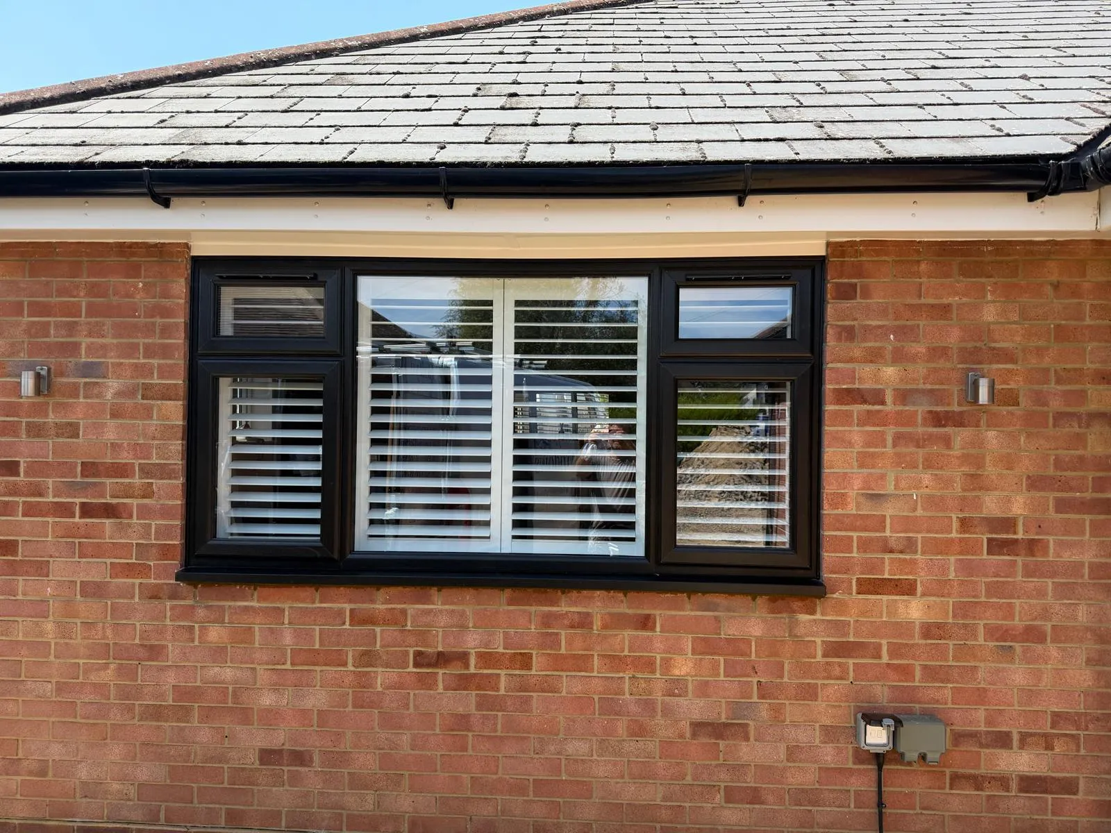 Black guttering and fascia beneath a slate roof on a brick bungalow