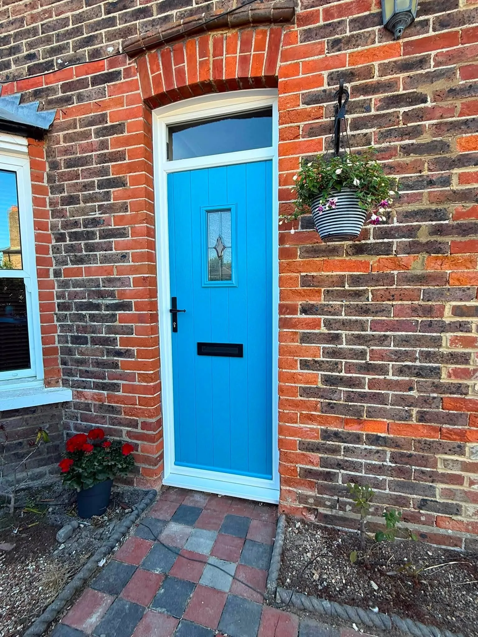 Bright blue composite front door with leaded glazing in a red brick cottage