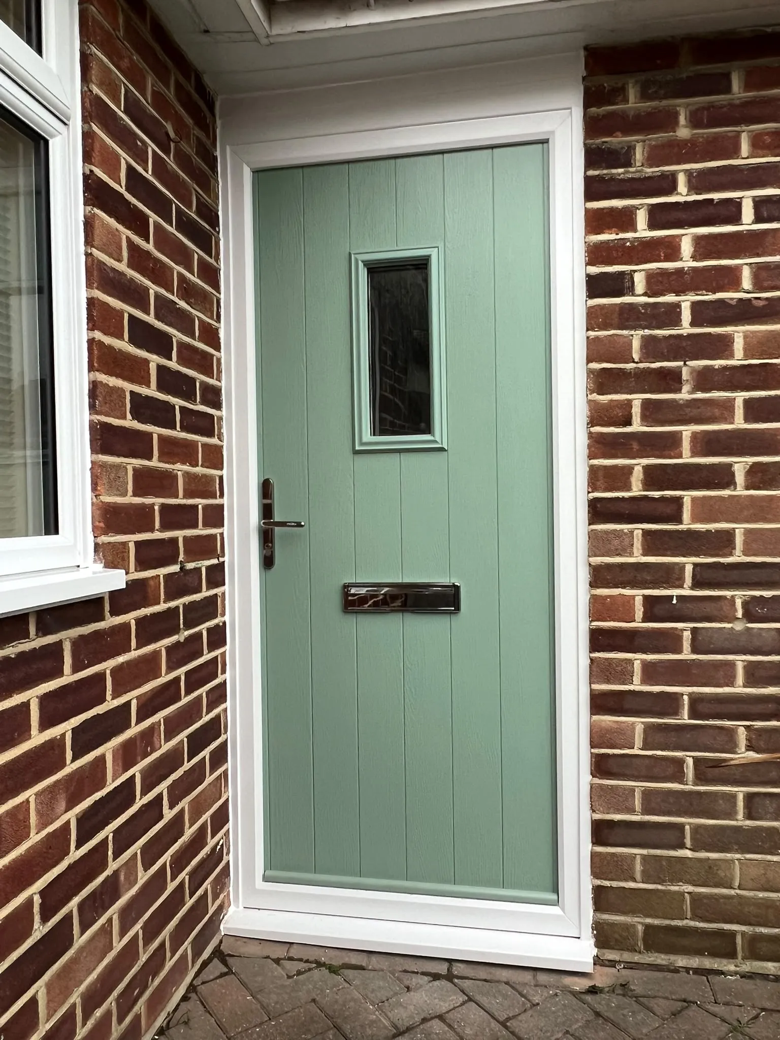 Chartwell green cottage-style composite front door with a small glazed panel and a black handle