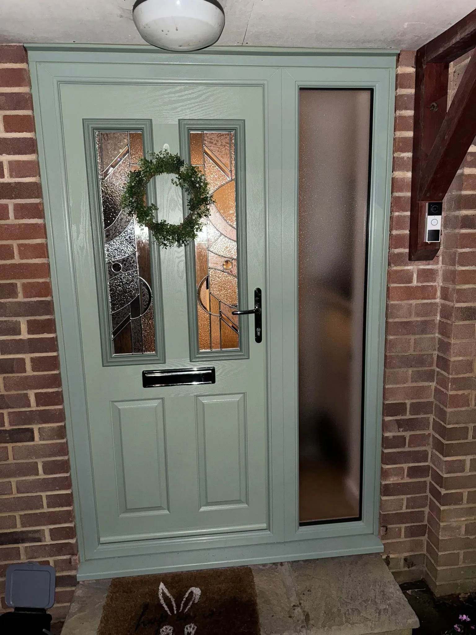 Sage green composite front door with glazed panels on a brick home