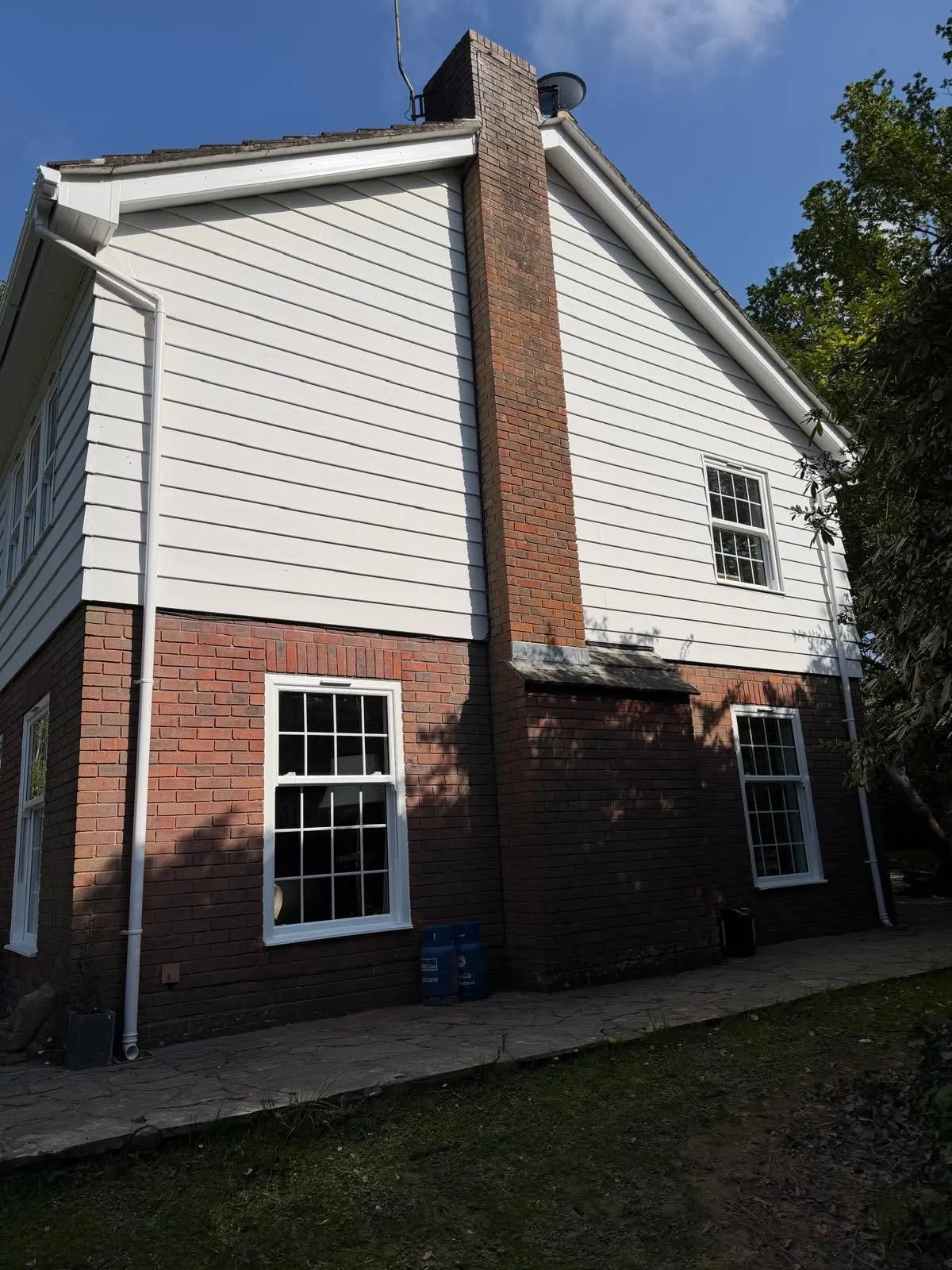 Gable end of the house with white weatherboarding, new white fascias and guttering, and Georgian-bar sash windows