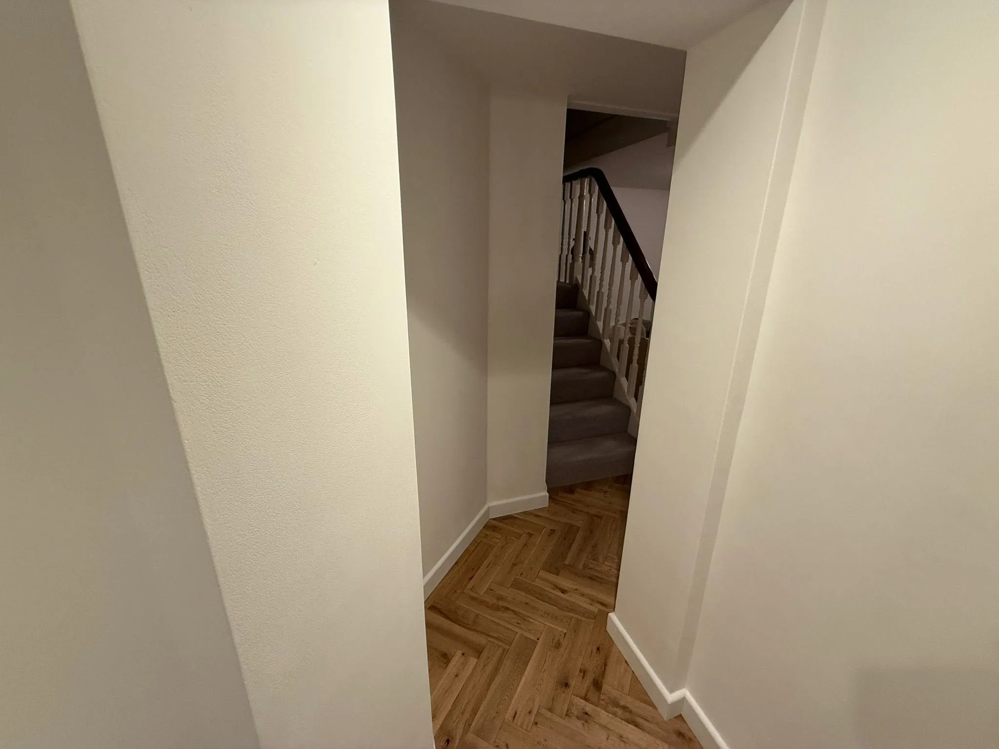 Freshly plastered and painted hallway with herringbone flooring leading to the stairs