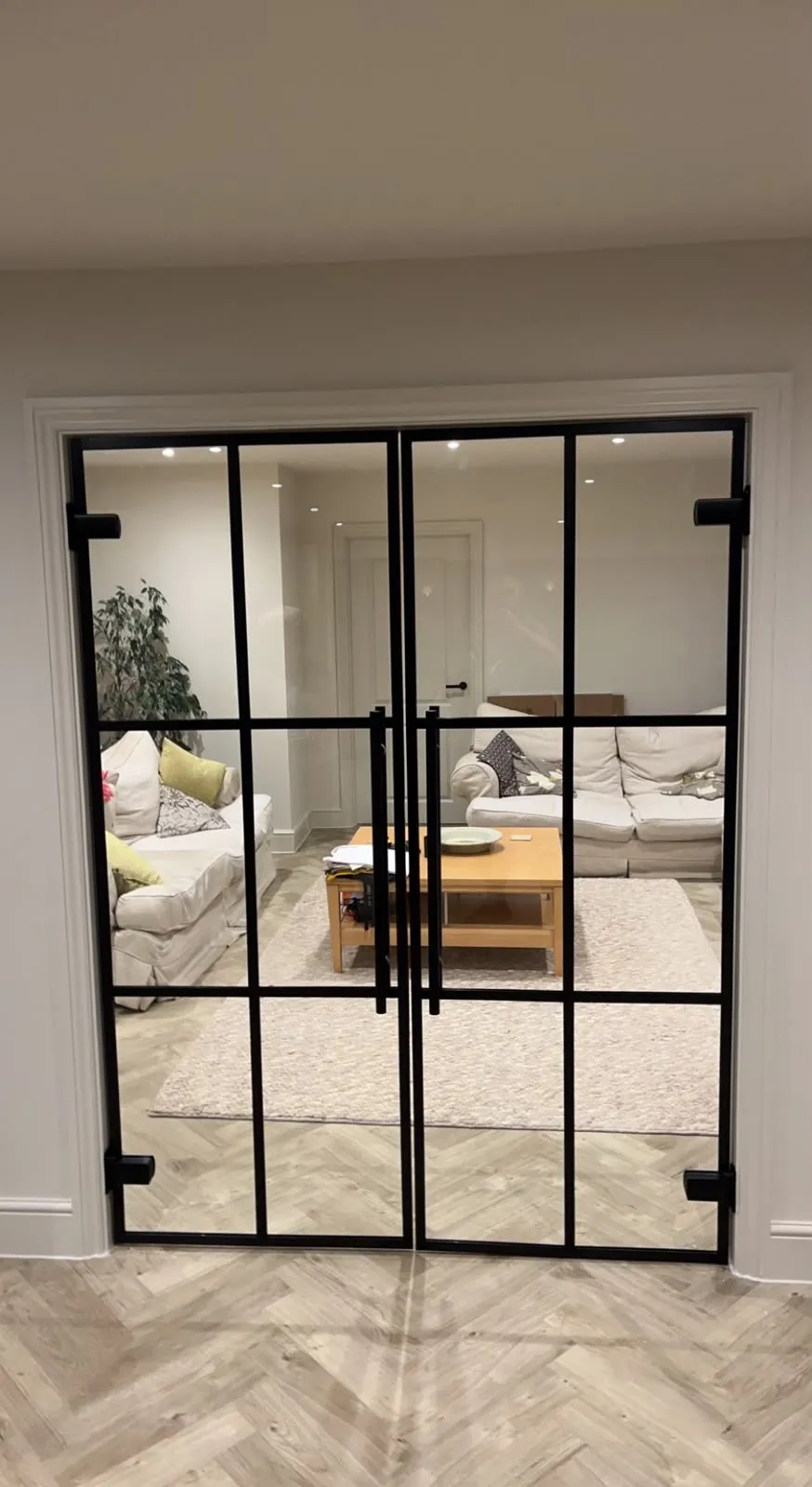 Black heritage-style internal double doors between a hallway and a living room