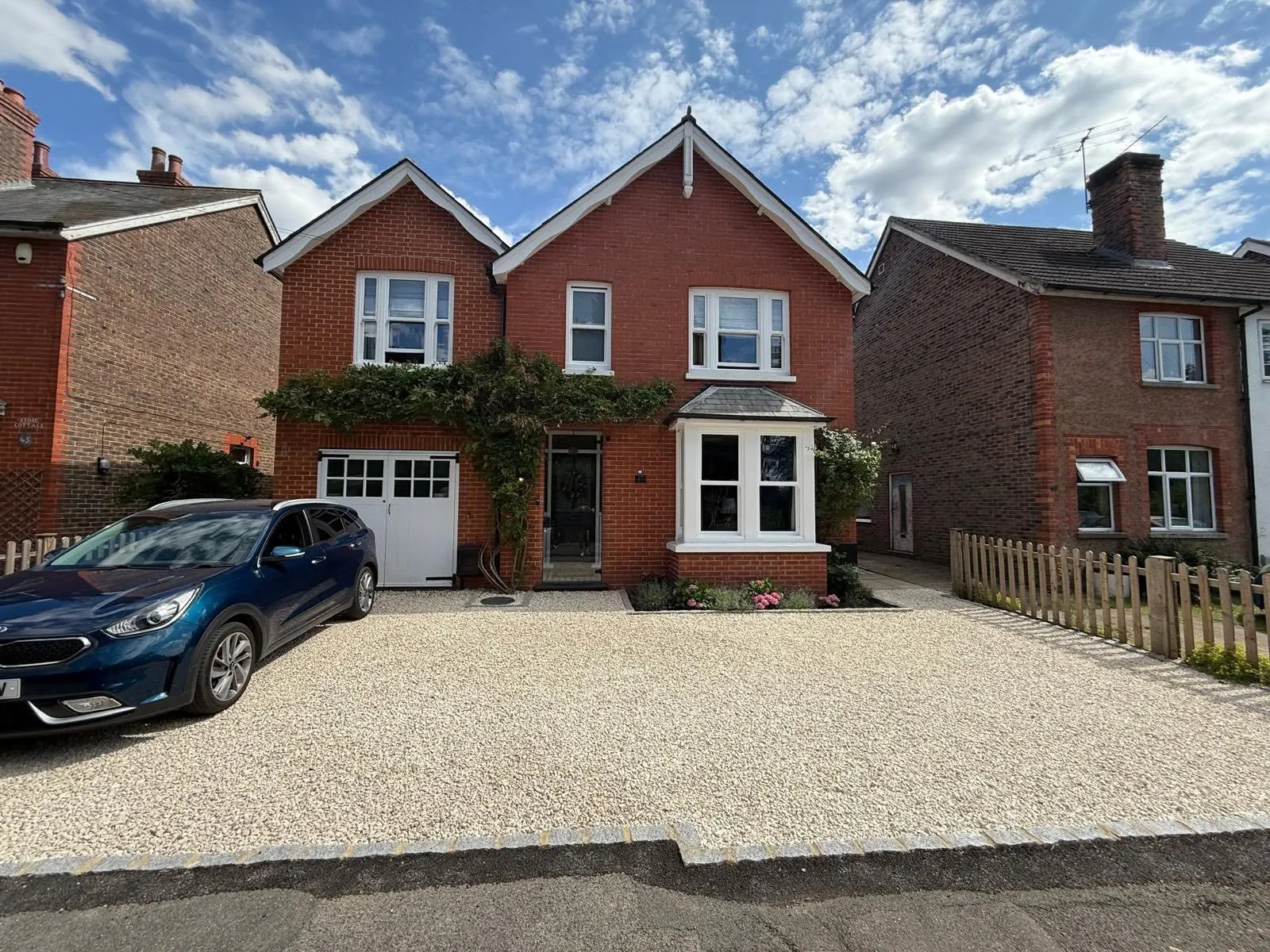 Red brick detached home in East Grinstead with white replacement bay and casement windows