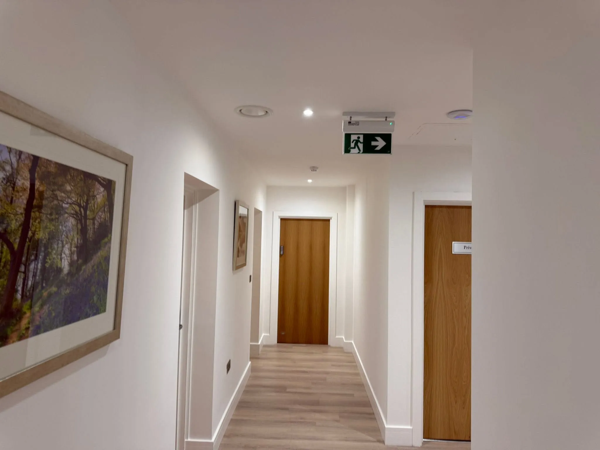 New corridor with oak doors, wood-effect flooring and emergency exit signage