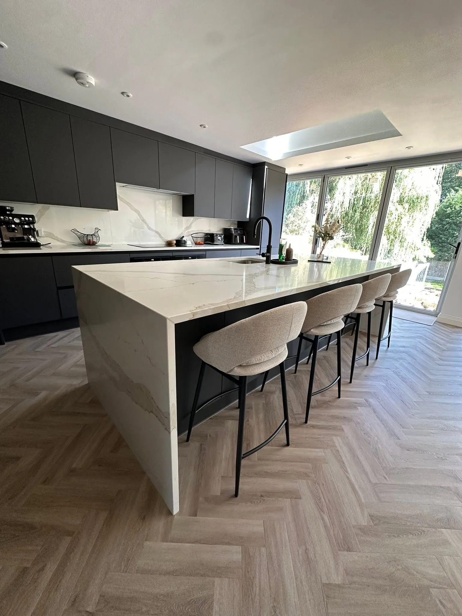 Dark fitted kitchen with an island and bar stools