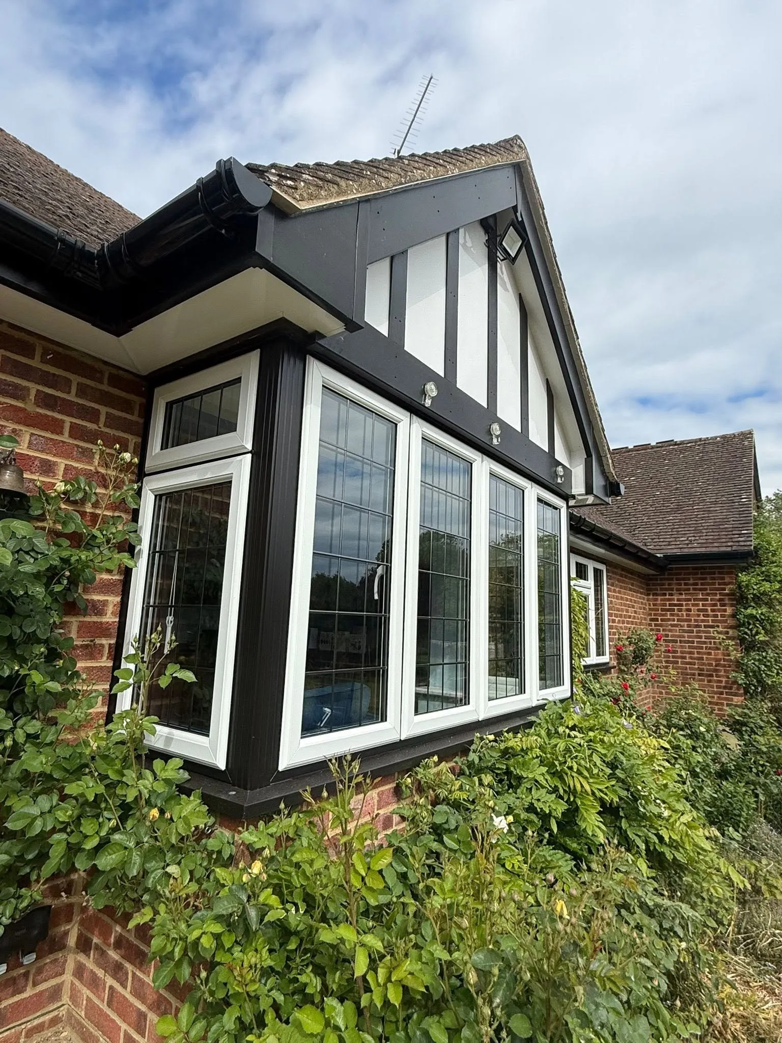 White bay window with leaded glass beneath a mock Tudor gable