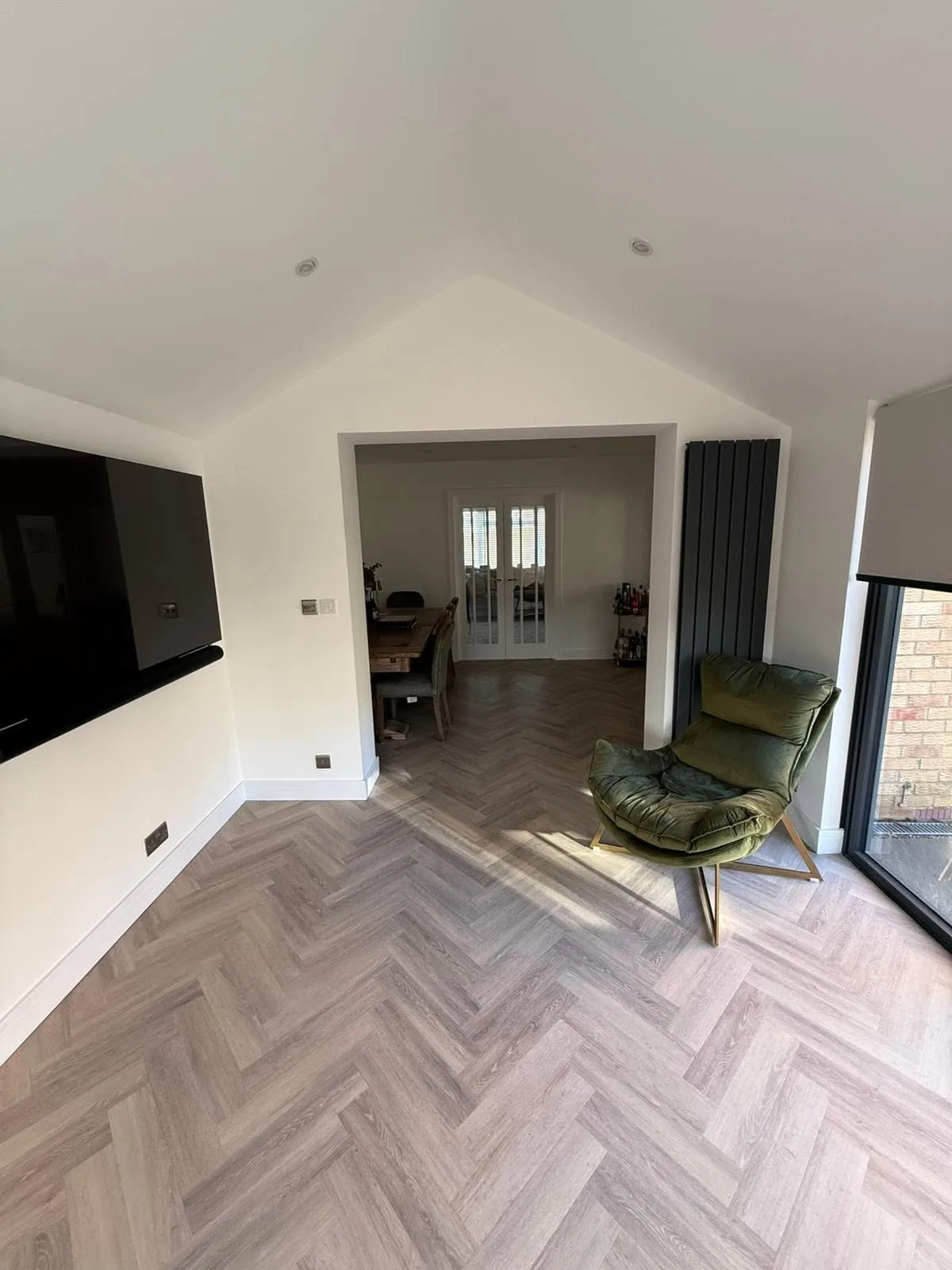 Living room with a herringbone wood floor and green armchairs