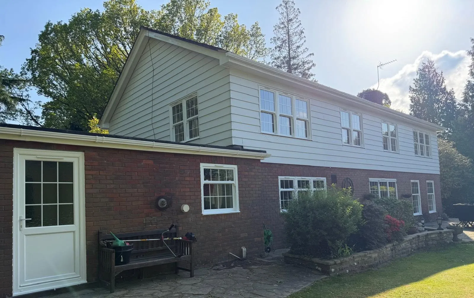 Single-storey wing with a new white half-glazed door, fascia and guttering, and the main house behind