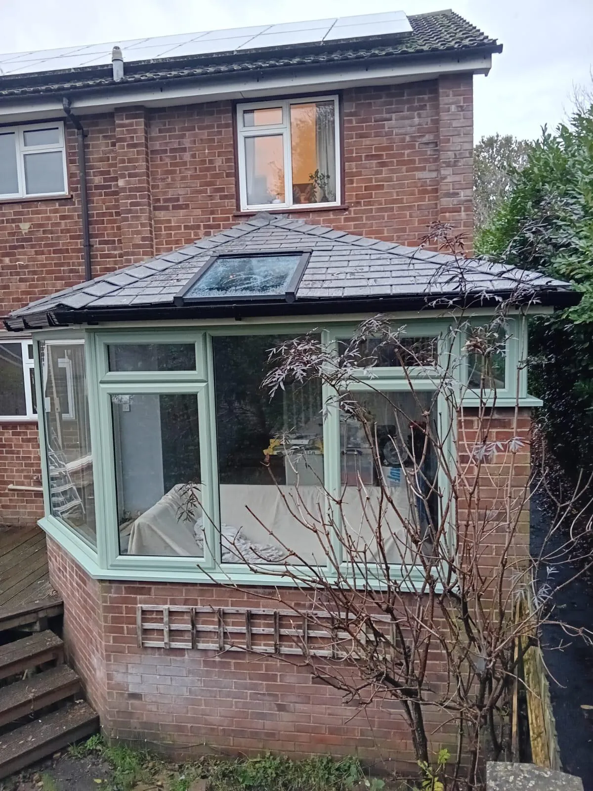 Sage green orangery with a solid roof and a glazed rooflight