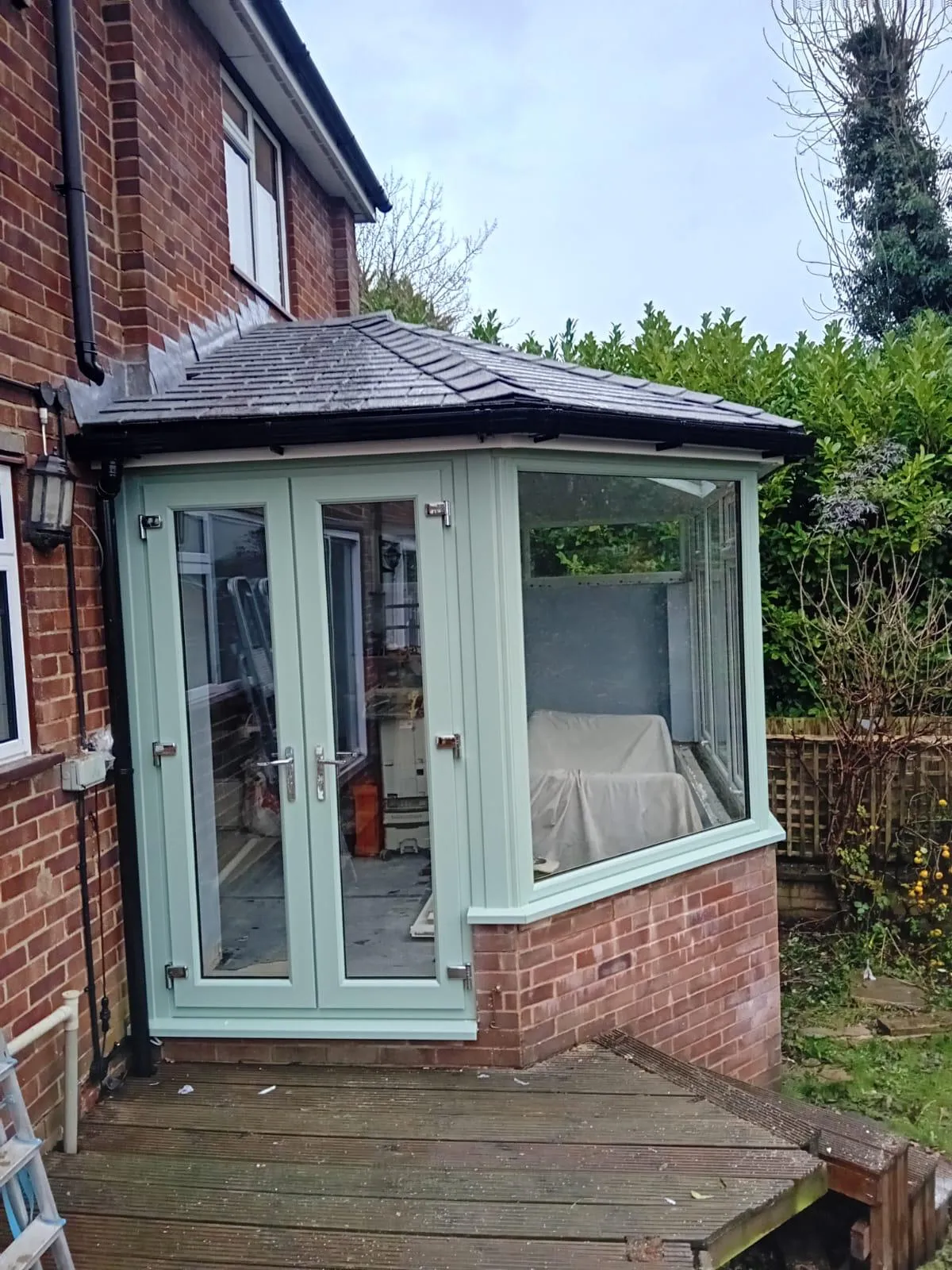 Sage green Victorian style conservatory on a brick bungalow