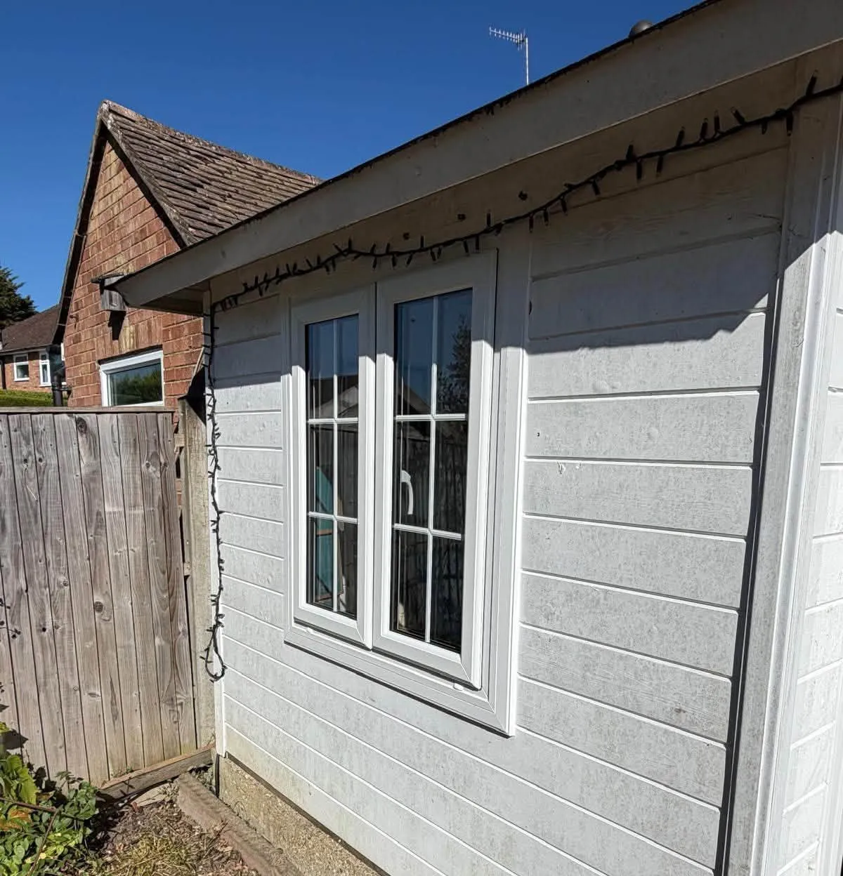 New white PVCu window with Georgian bars in the side wall of the timber summer house