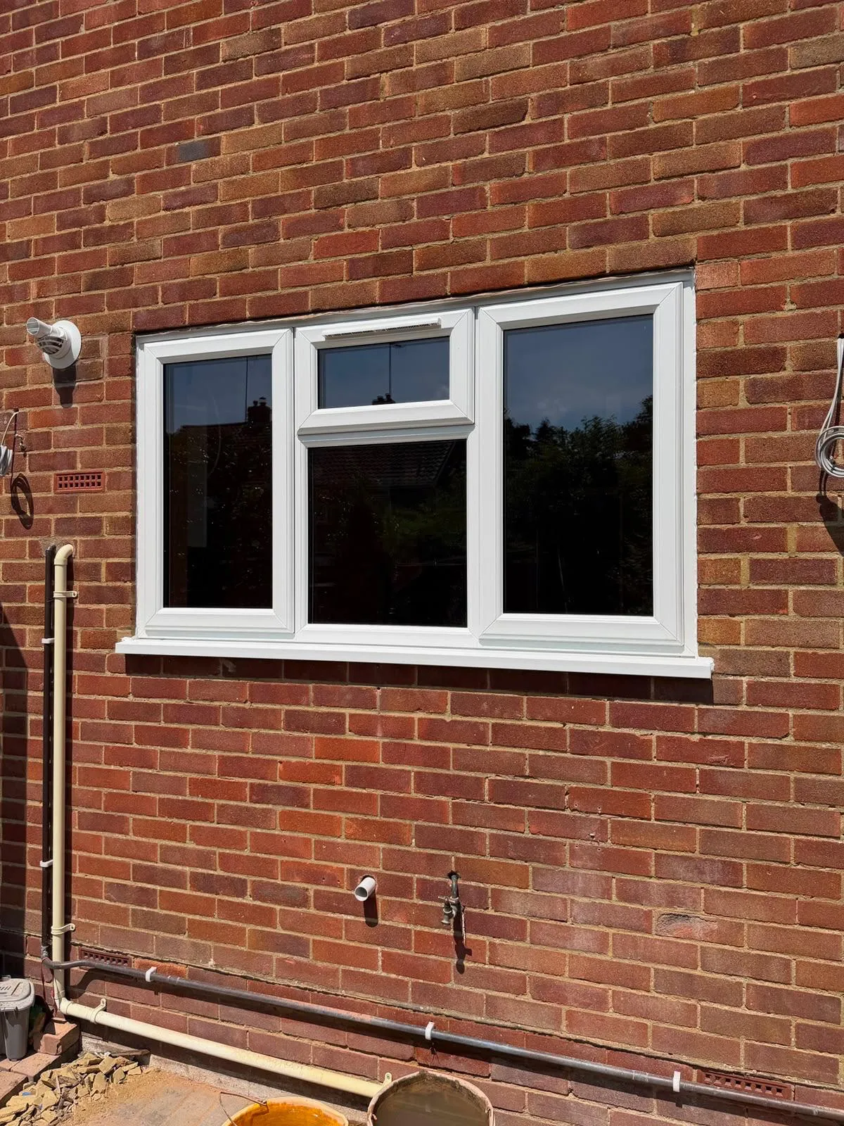White casement window with a top opening vent in a brick wall
