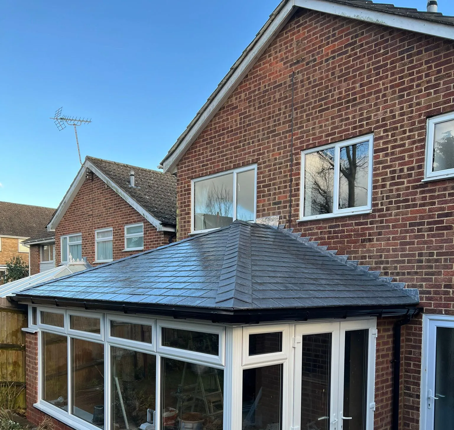 White conservatory with a slate-effect tiled warm roof on a brick home