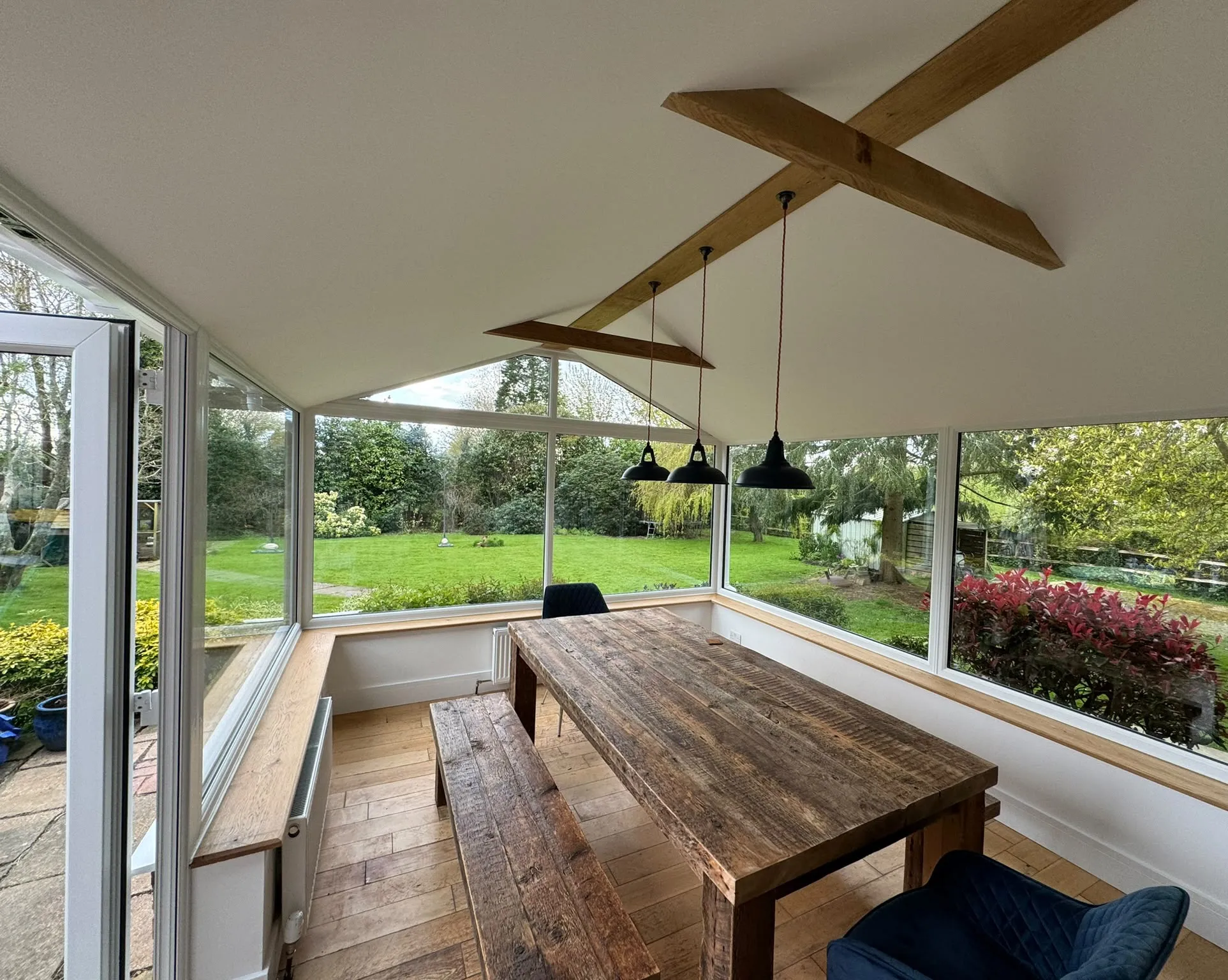 Inside a warm roof conservatory with a plastered vaulted ceiling, oak beams and pendant lights