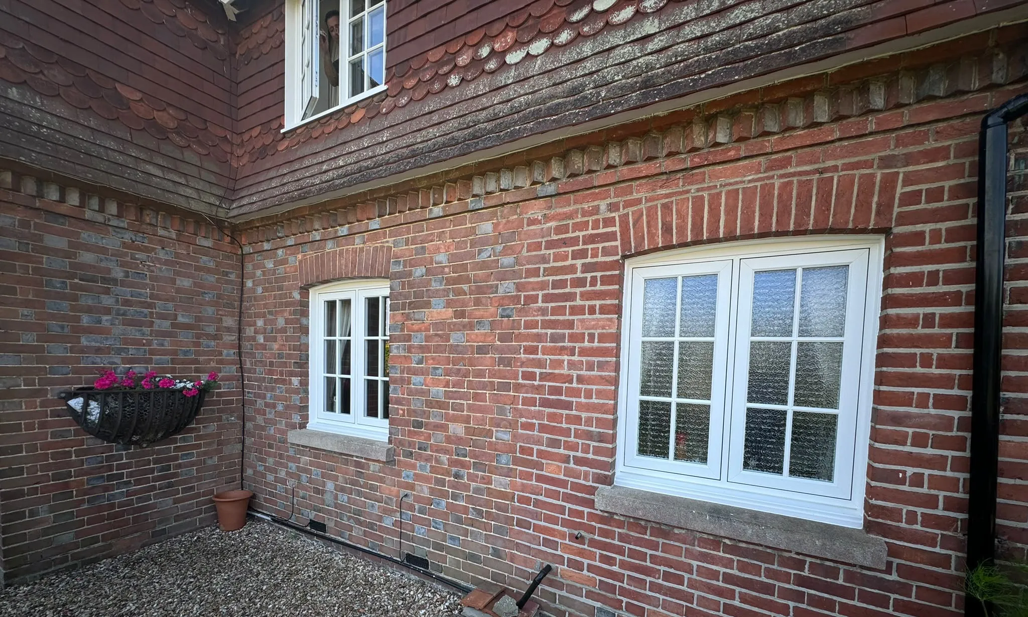 White casement windows with Georgian bars and stone cills on a brick cottage