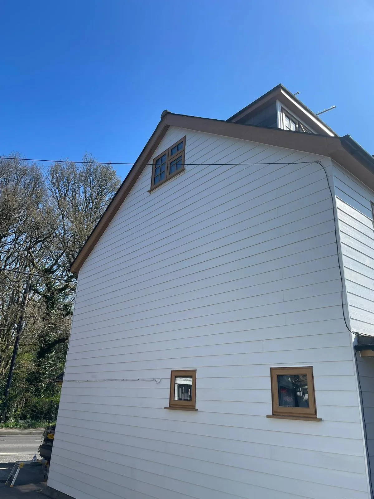 Gable end finished in white cladding, with oak-effect bargeboards and two small windows