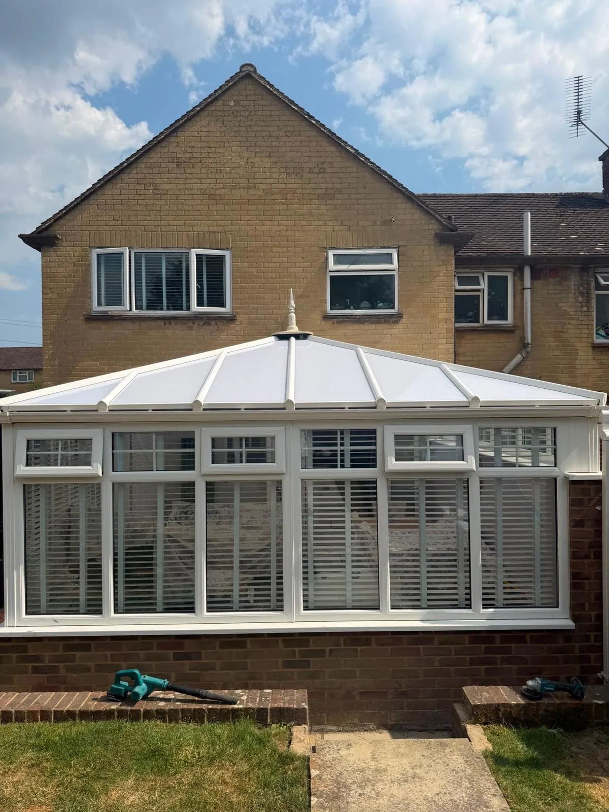White conservatory with a solid tiled roof and internal shutters