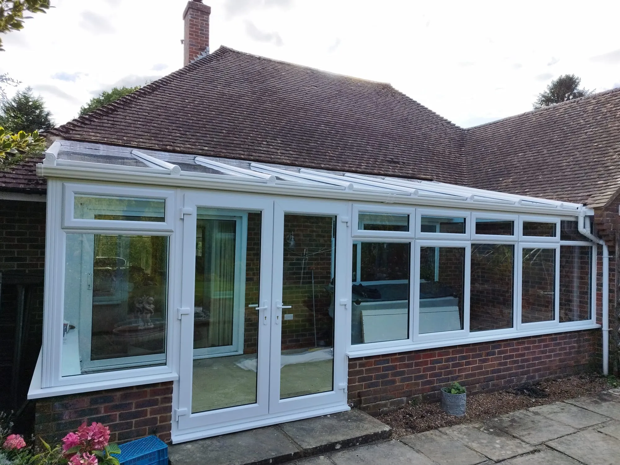White uPVC lean-to conservatory with a glass roof and French doors on a bungalow