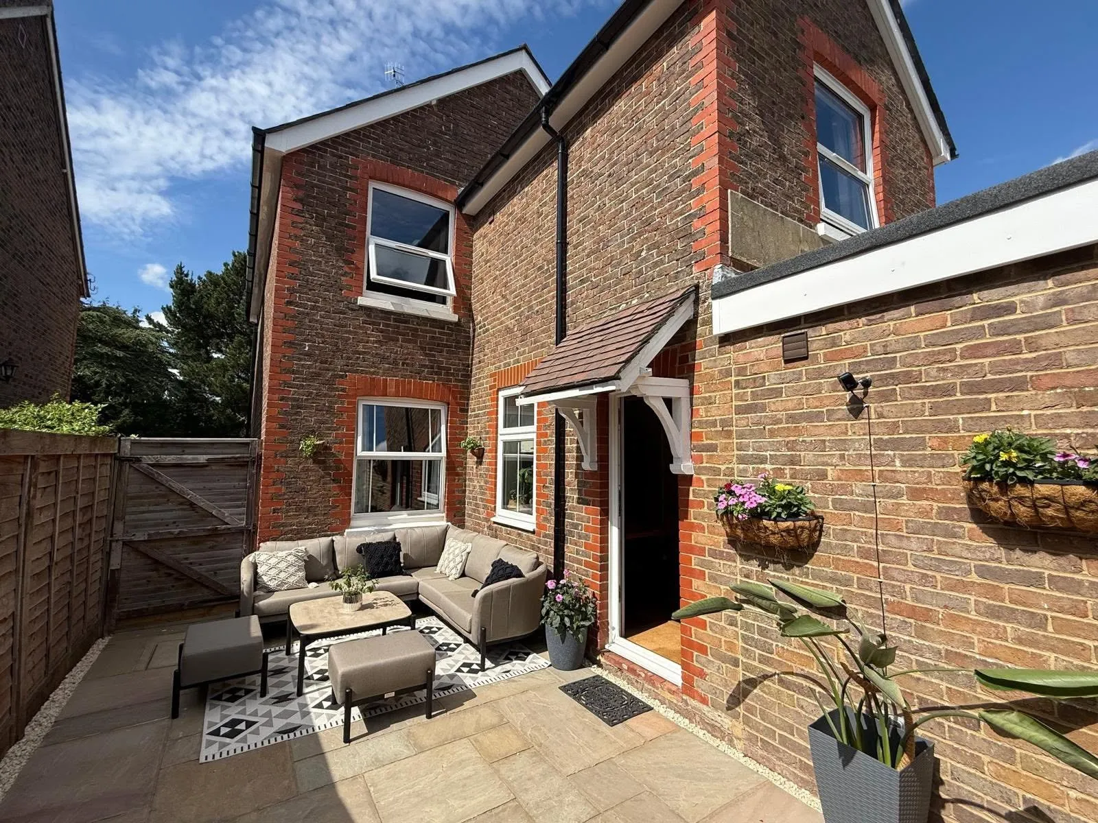 Back of the house with new white sash windows and a tiled door canopy, above a sandstone patio with outdoor seating