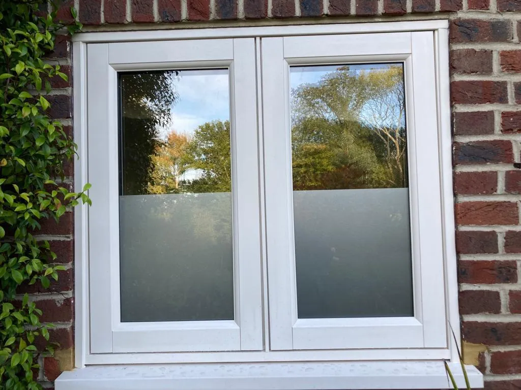 White casement window fitted into a red brick wall
