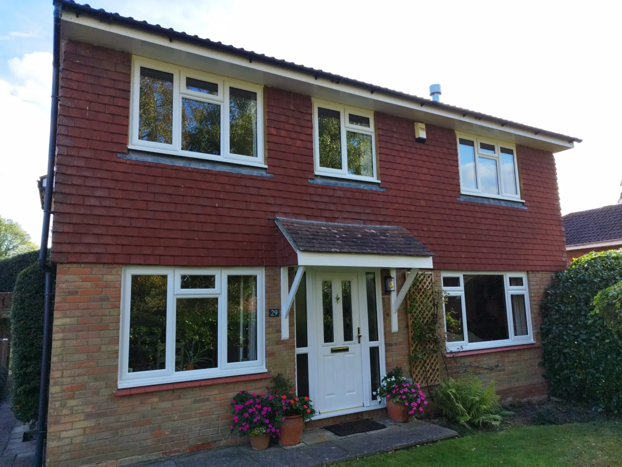Detached brick and tile-hung home with white uPVC casement windows and a white front door