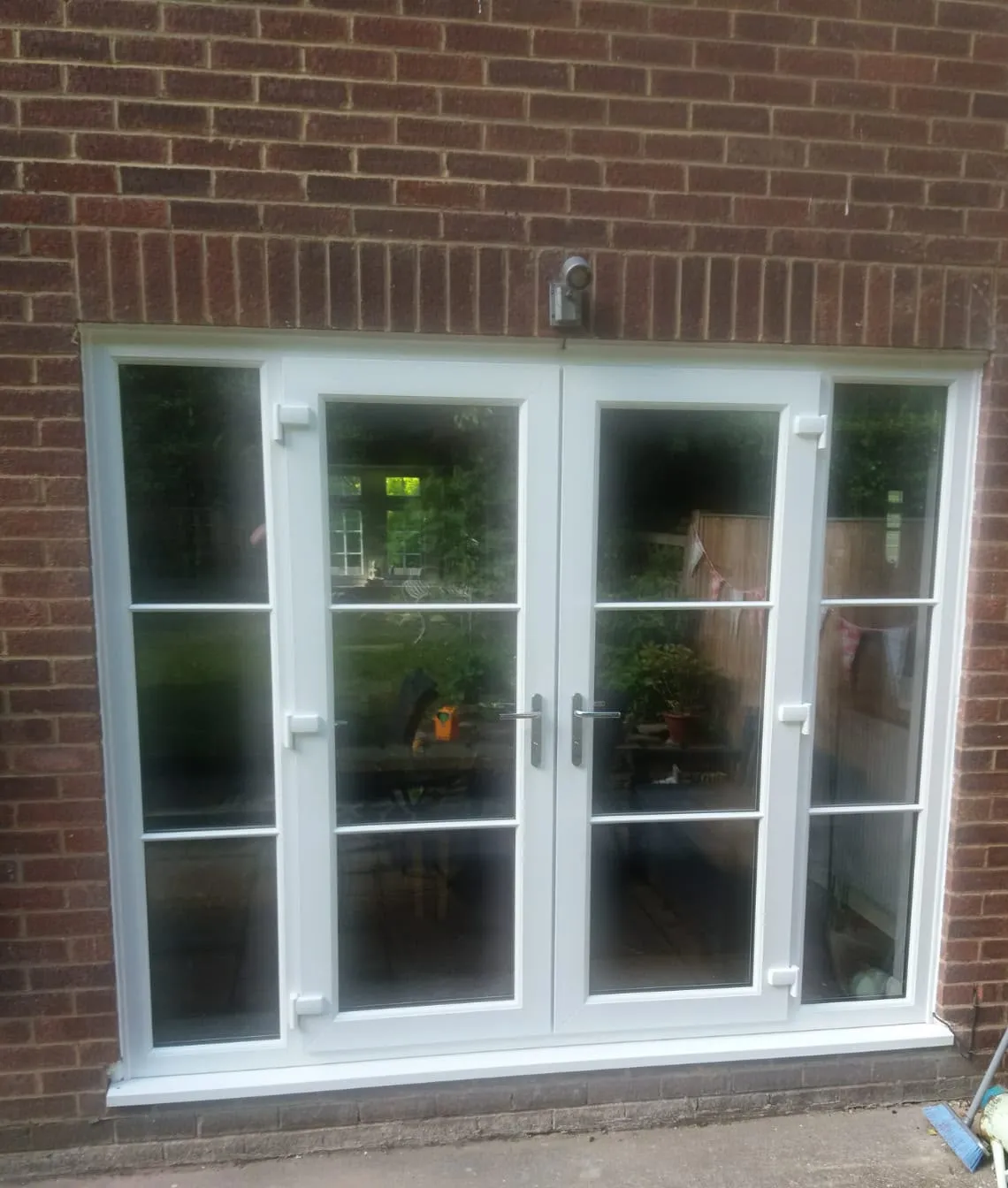 White uPVC French doors with Georgian bars and glazed side lights in a brick wall